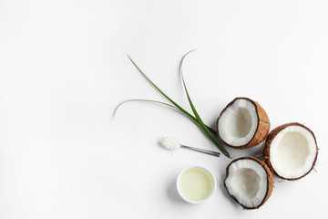 Bowl of natural organic oil and coconuts on white background, top view