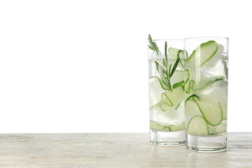 Glasses of refreshing cucumber lemonade on wooden table against white background, space for text. Summer drink