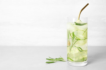 Glass of refreshing cucumber lemonade on table against light background, space for text. Summer drink