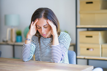 Middle age senior woman sitting at the table at home suffering from headache desperate and stressed...
