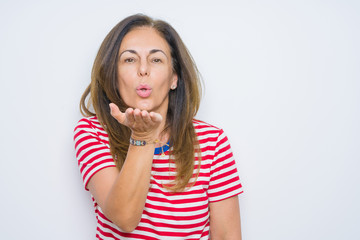 Middle age senior woman standing over white isolated background looking at the camera blowing a kiss with hand on air being lovely and sexy. Love expression.