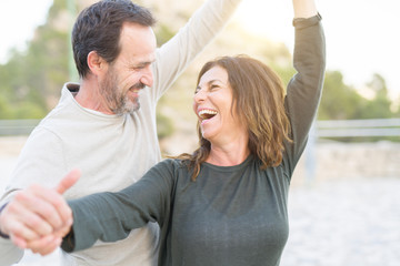 Romantic couple smiling and dancing on a sunny day