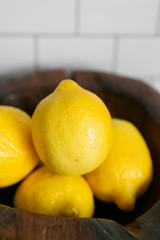 Wooden Bowl of Lemons On Concrete Kitchen Countertop, White Subway Tile Background, Close Up View