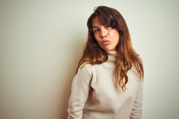 Young beautiful woman wearing winter sweater standing over white isolated background looking at the camera blowing a kiss on air being lovely and sexy. Love expression.
