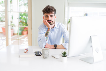 Young business man working using computer thinking looking tired and bored with depression problems with crossed arms.