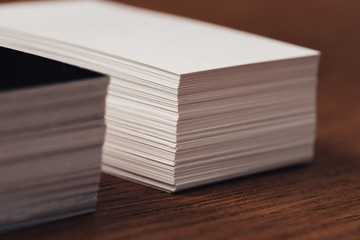 selective focus of stacked white and black empty business cards on brown wooden surface