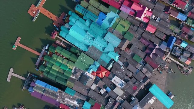 An aerial shot of the colorful roofs of houses and a big mosque in a settlement surrounded by water in Thailand