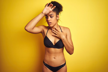 African american woman on vacation wearing bikini standing over isolated yellow background Touching forehead for illness and fever, flu and cold, virus sick