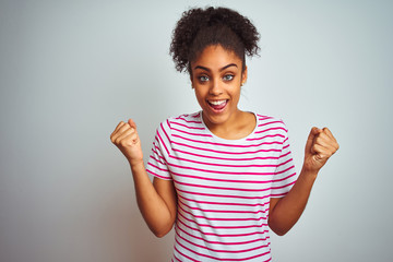 African american woman wearing casual pink striped t-shirt over isolated white background celebrating surprised and amazed for success with arms raised and open eyes. Winner concept.