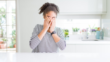 Beautiful african american woman with afro hair wearing casual striped sweater rubbing eyes for...