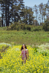Fototapeta premium Mixed race young woman stands in a flower field on a farm