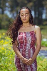 Fototapeta premium Mixed race young woman stands in a flower field on a farm