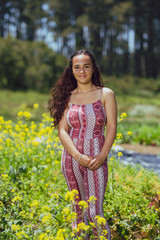 Naklejka na ściany i meble Mixed race young woman stands in a flower field on a farm