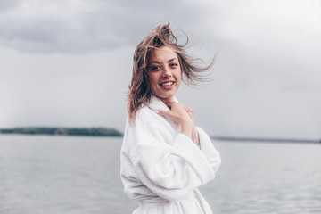 a girl in a white coat on the waterfront by the water.cloudy weather