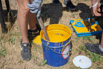 Paint brush. Man paints objects in the yard. Work with color. It's time to upgrade the garden.