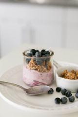 Blueberry Yogurt in Clear Glass with Fresh Blueberries and Honey Granola, Modern Kitchen Background, Spoon