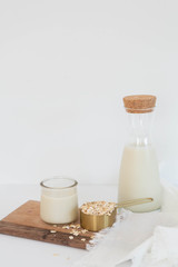 Homemade Oat Milk Glass and Oats with Jug of Milk, White Background, Copy Space
