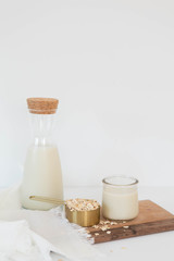 Homemade Oat Milk Glass and Oats with Jug of Milk, White Background, Copy Space