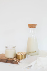 Homemade Oat Milk Glass and Oats with Jug of Milk, White Background, Copy Space