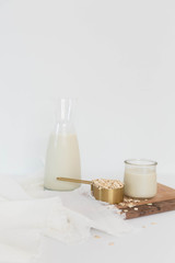 Homemade Oat Milk Glass and Oats with Jug of Milk, White Background, Copy Space