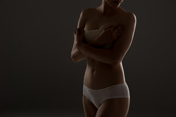 cropped view of woman in panties with breast bandage in darkness - obrazy, fototapety, plakaty