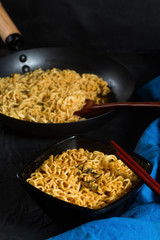 Ramen noodles bowl on a dark textured background with dark wooden chopsticks