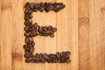 Alphabet letter E made from roasted coffee beans, 3D rendering on wooden table background