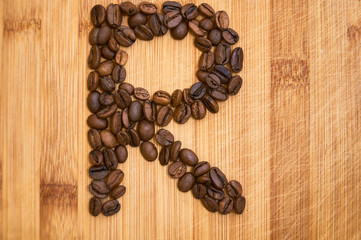 Alphabet letter R made from roasted coffee beans, 3D rendering on wooden table background