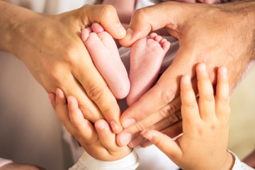 Newborn baby foots with family hands.