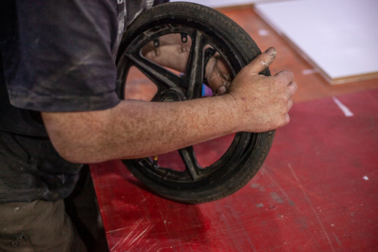 Master repairs the wheel. Wheel repair on a scooter. Work in a workshop on cars. Manual labor.