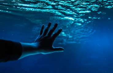 Human hand wants to reach the depths of the ocean. The concept of saving the ocean from pollution