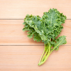 Fresh organic curly kale leaves flat lay on a wooden table with copy space.