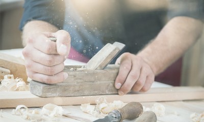 carpenter working  with  plane  on wooden background