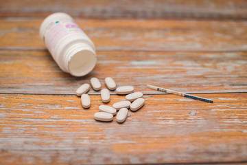 Fototapeta na wymiar maternal and child health care. gray capsules with multivitamins for pregnant women and pregnancy test on wooden table.