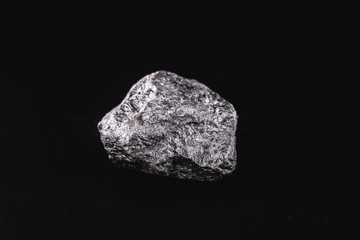 Manganese in the raw state. Manganese stone isolated on black background. Mineral extraction of heavy metal.