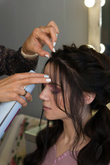 Hairstylist fixes textured tress using hair spray. Hairdressing services. Process of creating hairdo. Hairdresser makes hairstyle to client. Beauty industry