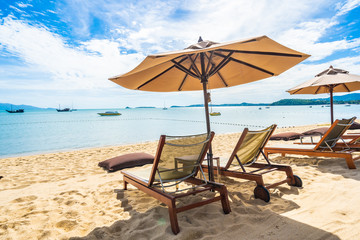 Beautiful tropical beach sea and ocean with coconut palm tree  and umbrella and chair on blue sky and white cloud