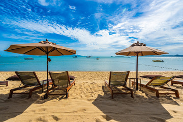 Beautiful tropical beach sea and ocean with coconut palm tree  and umbrella and chair on blue sky and white cloud