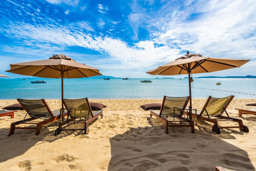 Beautiful tropical beach sea and ocean with coconut palm tree  and umbrella and chair on blue sky and white cloud