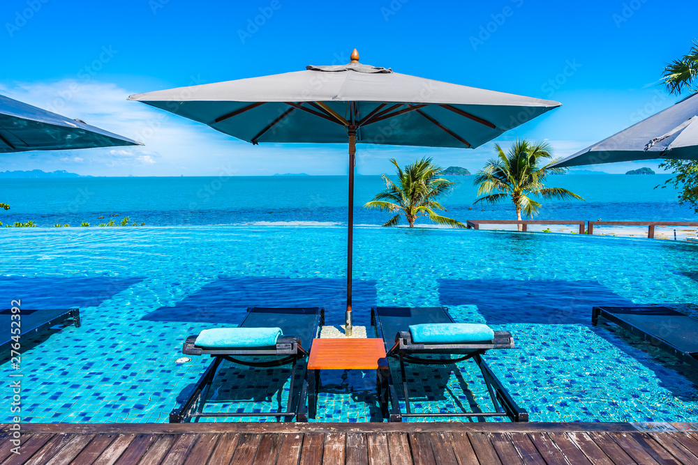 Sticker Beautiful luxury outdoor swimming pool in hotel resort with sea ocean around coconut palm tree and white cloud on blue sky