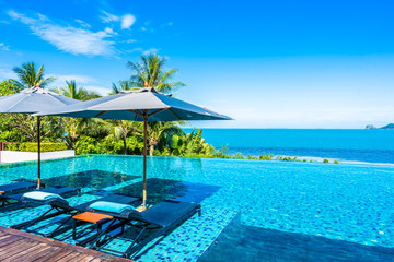 Beautiful luxury outdoor swimming pool in hotel resort with sea ocean around coconut palm tree and white cloud on blue sky - obrazy, fototapety, plakaty