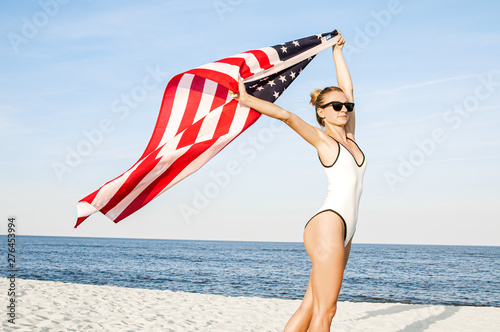 Beautiful patriotic woman holding an American flag on the beach.  USA Independence day, 4th July.