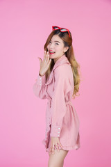 Obraz na płótnie Canvas Fashion girl dress up with a hand gesture on a pink background.