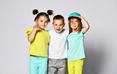 full body shot of three children in bright clothes, two girls and one boy. Triplets, brother and sisters.