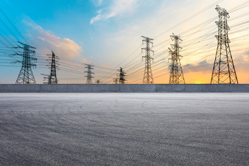 Empty asphalt road and high voltage power tower landscape