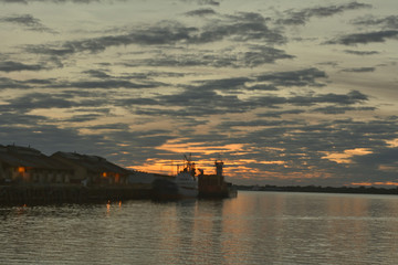 Fototapeta na wymiar Atardecer en el puerto con muchas nubes y y el suave color del sol