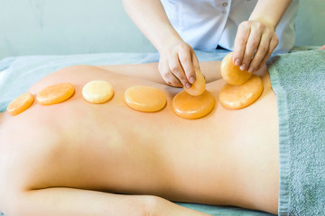 Treatment of the back and spine with yellow jade. The girl on the massage table treats back. Masseur doing massage. Yellow jade and massage.