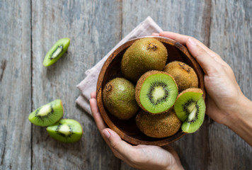 Fresh kiwi fruit in the bowl on wooden background - obrazy, fototapety, plakaty