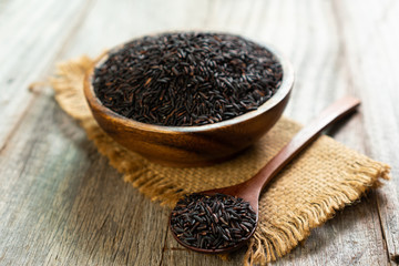 rice berry in wooden bowl with spoon on wooden table