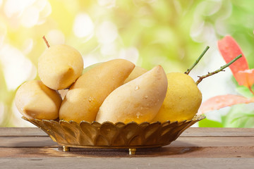 Mango on wooden table with sunlight background.